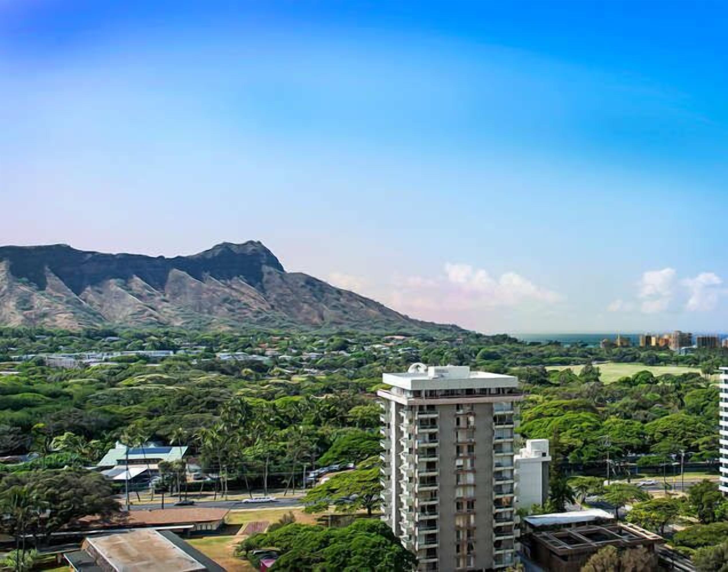 Un edificio de gran altura con vistas a una montaña y un parque.