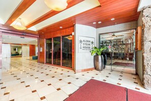 A hotel lobby with a modern design, featuring a checkered floor pattern, a reception desk, and a sign for Aloha Steak House. - Ocean-mt Renovated Marine Surf Condo by the Beach W/parking and Kitchenette (Honolulu)