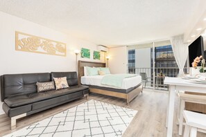 A modern bedroom with a bed, a sofa, a desk, and a balcony. - Ocean-mt Renovated Marine Surf Condo by the Beach W/parking and Kitchenette (Honolulu)