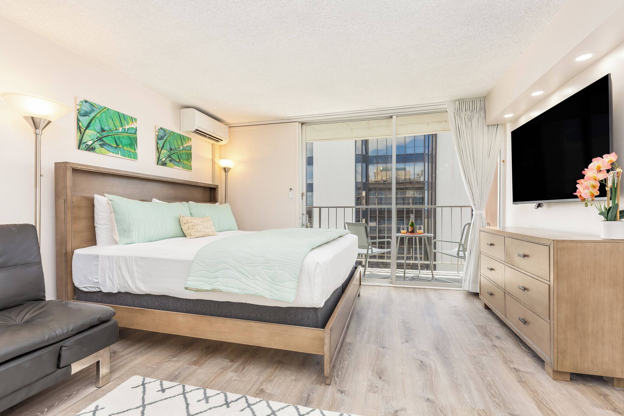 A modern hotel room with a bed, a desk, a chair, and a TV.