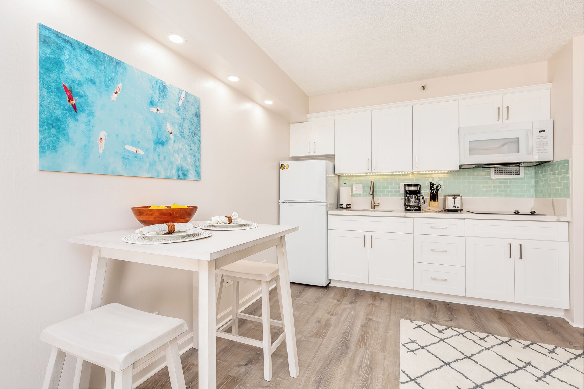 A modern kitchen with white cabinets, a white countertop, a microwave, and a coffee maker.