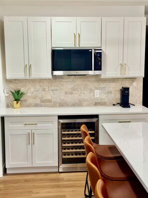 A modern kitchen with white cabinetry, a built-in microwave, a coffee maker, and a dishwasher. - Modern Home in the vibrant Ohio city neighborhood (Cleveland)