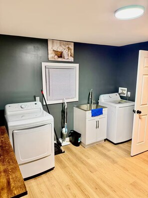 A laundry room with two washing machines, a sink, and a window with blinds. - Modern Home in the vibrant Ohio city neighborhood (Cleveland)