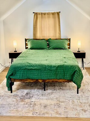 A bedroom with a bed, two bedside tables, a window with curtains, and a wooden floor. - Modern Home in the vibrant Ohio city neighborhood (Cleveland)