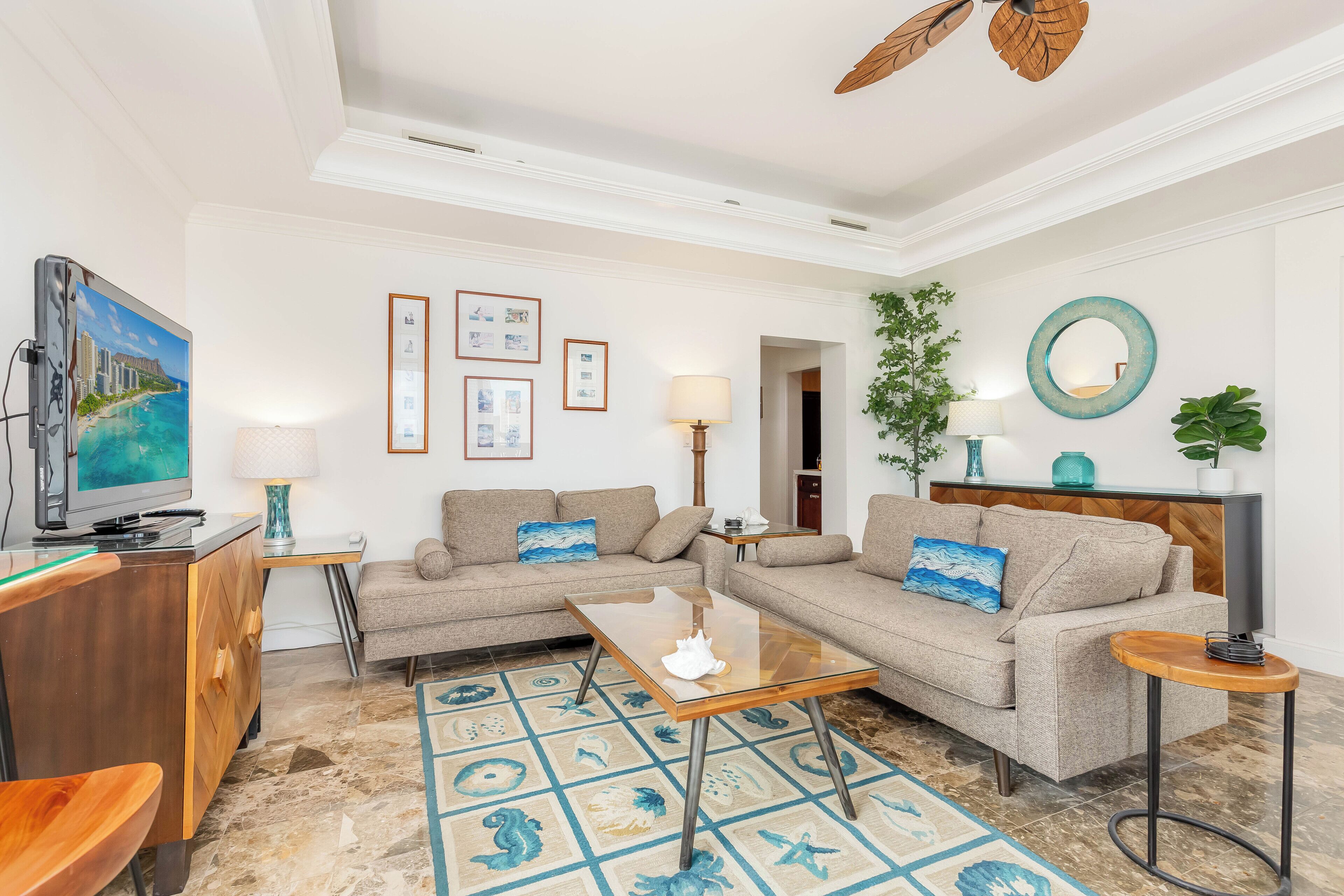 A modern living room with two sofas, a glass coffee table, a wooden side table, a TV, and a decorative rug.