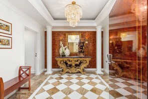 A grand hallway with a checkered floor, a large ornate console table, and a chandelier. - Ocean-city Panoramic PH Condo at the Royal Garden W/amazing Hotel Amenities (Honolulu)