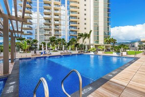 A swimming pool with a wooden deck, lounge chairs, and palm trees. - Ocean-city Luxurious Vacation at the Sky Ala Moana With Amazing Amenities (Honolulu)