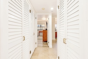 A hallway with white sliding doors and a kitchen area visible through an open door. - Ocean View Paradise Escape at Waikiki Beach Tower Near Shops & Restaurants (Honolulu)
