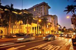 A multi-story hotel with a grand entrance, palm trees, and a busy street with cars. - Ocean View Paradise Escape at Waikiki Beach Tower Near Shops & Restaurants (Honolulu)