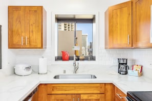 A kitchen with wooden cabinets, a stainless steel sink, a coffee maker, and a rice cooker. - Ocean View Paradise Escape at Waikiki Beach Tower Near Shops & Restaurants (Honolulu)