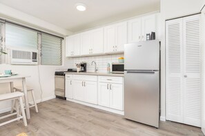 A compact kitchen with white cabinets, a stainless steel refrigerator, a coffee maker, and a microwave. - Remodeled Condo by the Beach at the Cabana Waikiki W/full Kitchen & Free Wifi (Honolulu)