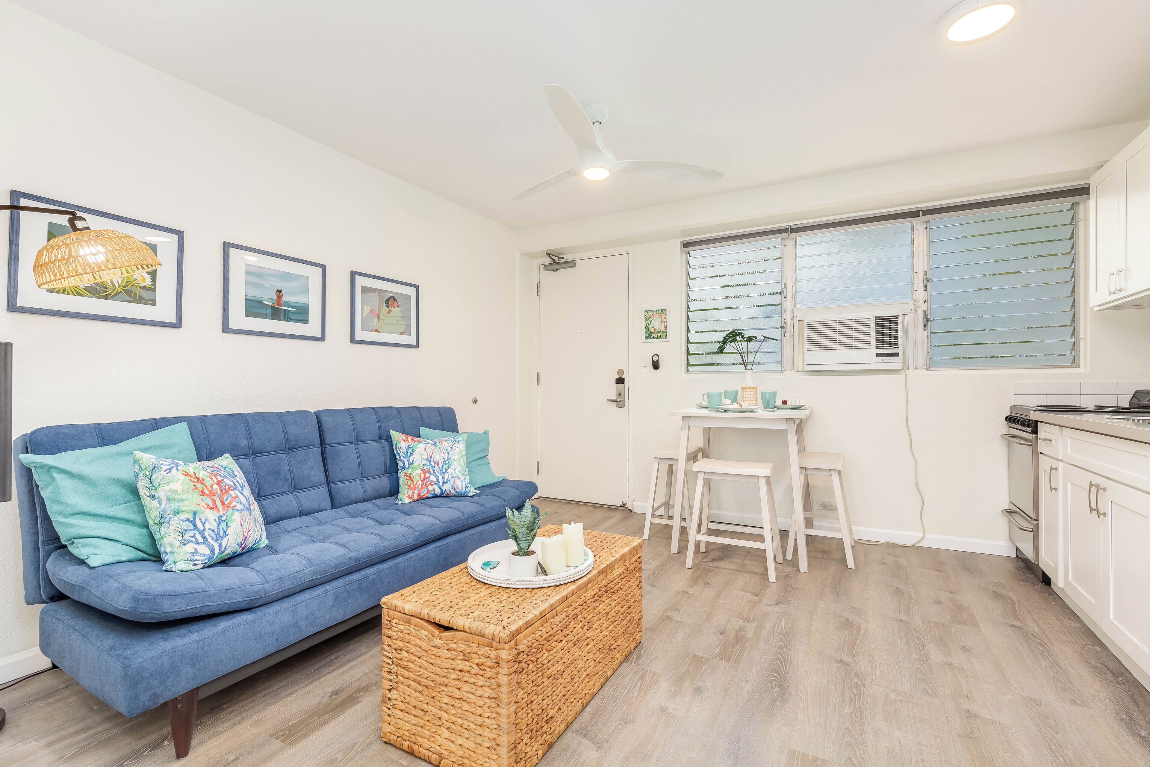 Ein modernes Wohnzimmer mit einem blauen Sofa, einem Korpus-Couchtisch und einem Essbereich mit einem weißen Tisch und Stühlen.