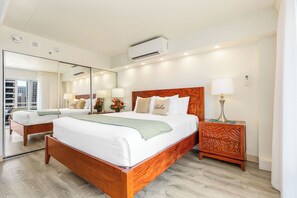 A hotel room with a large bed, a bedside table, a mirror, and an air conditioning unit. - Ocean & Fireworks Views Condo at the Ilikai Hotel W/full Kitchen & Free Wifi (Honolulu)