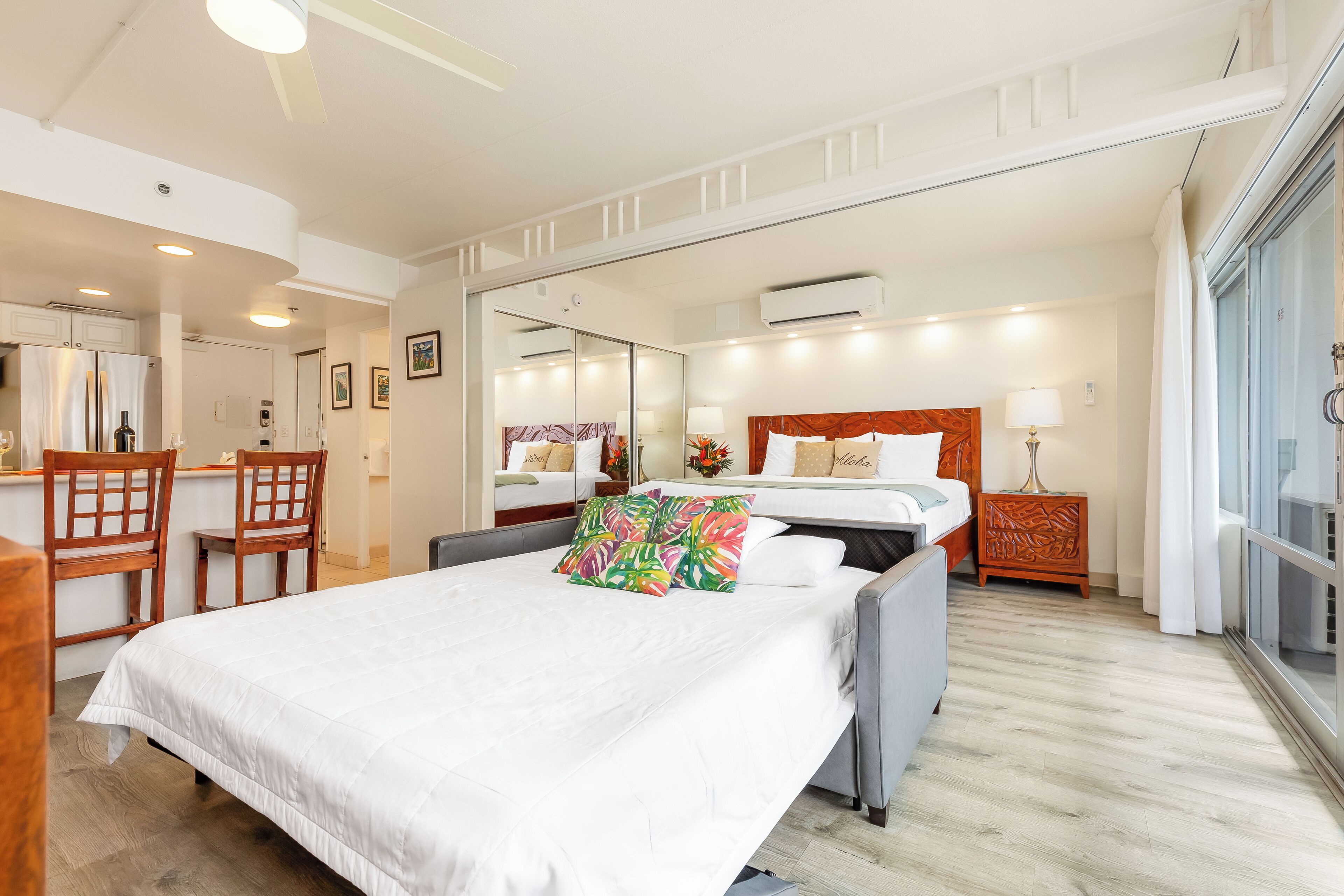 A hotel room with a bed, a desk, a chair, a mirror, and a window.