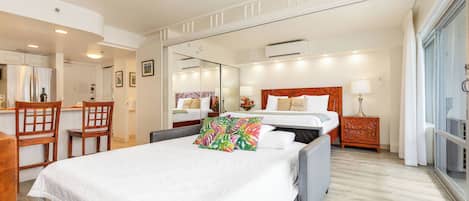A hotel room with a bed, a desk, a chair, a mirror, and a window.