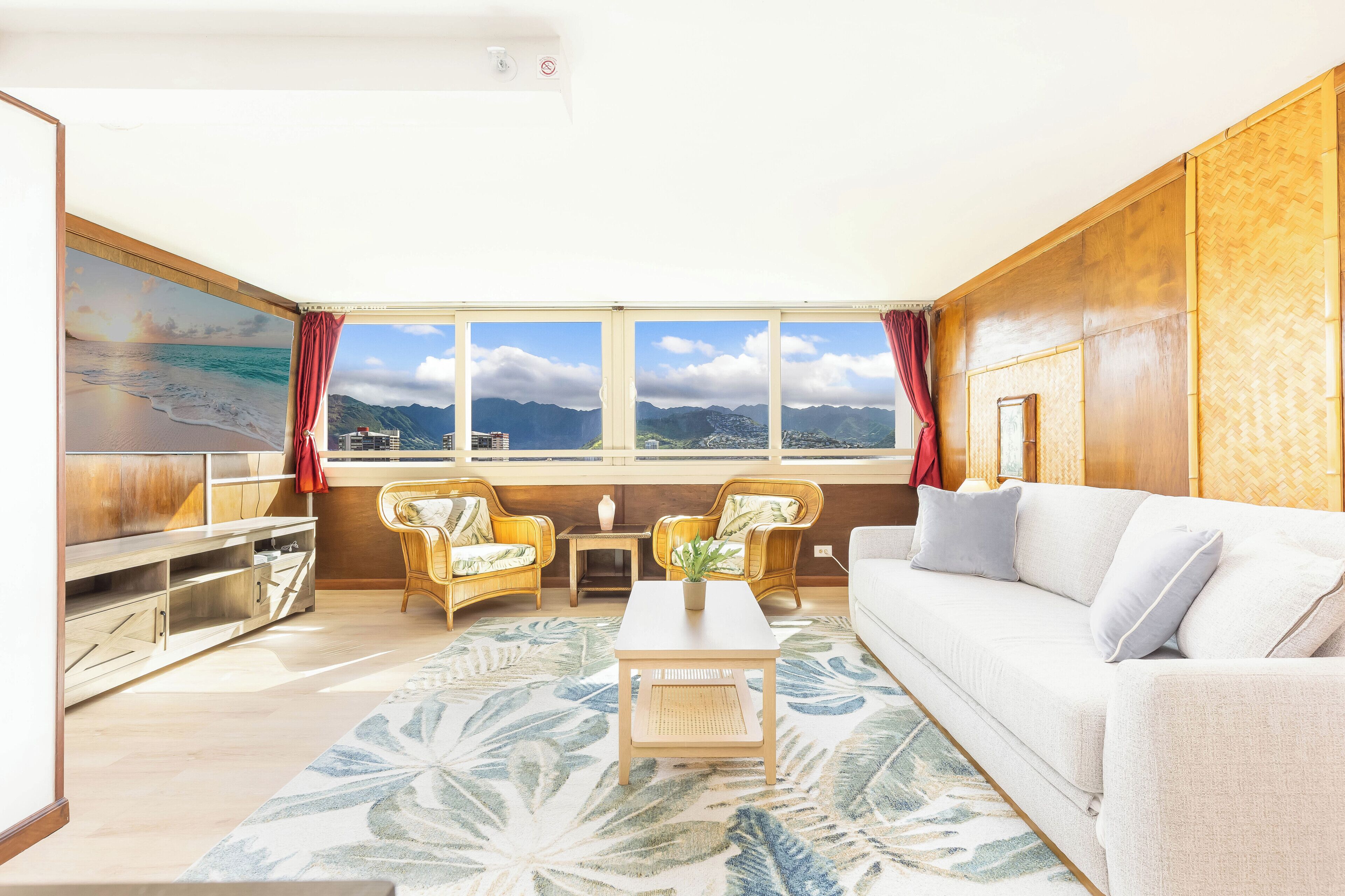 A living room with a large window, a sofa, two armchairs, a coffee table, and a TV.