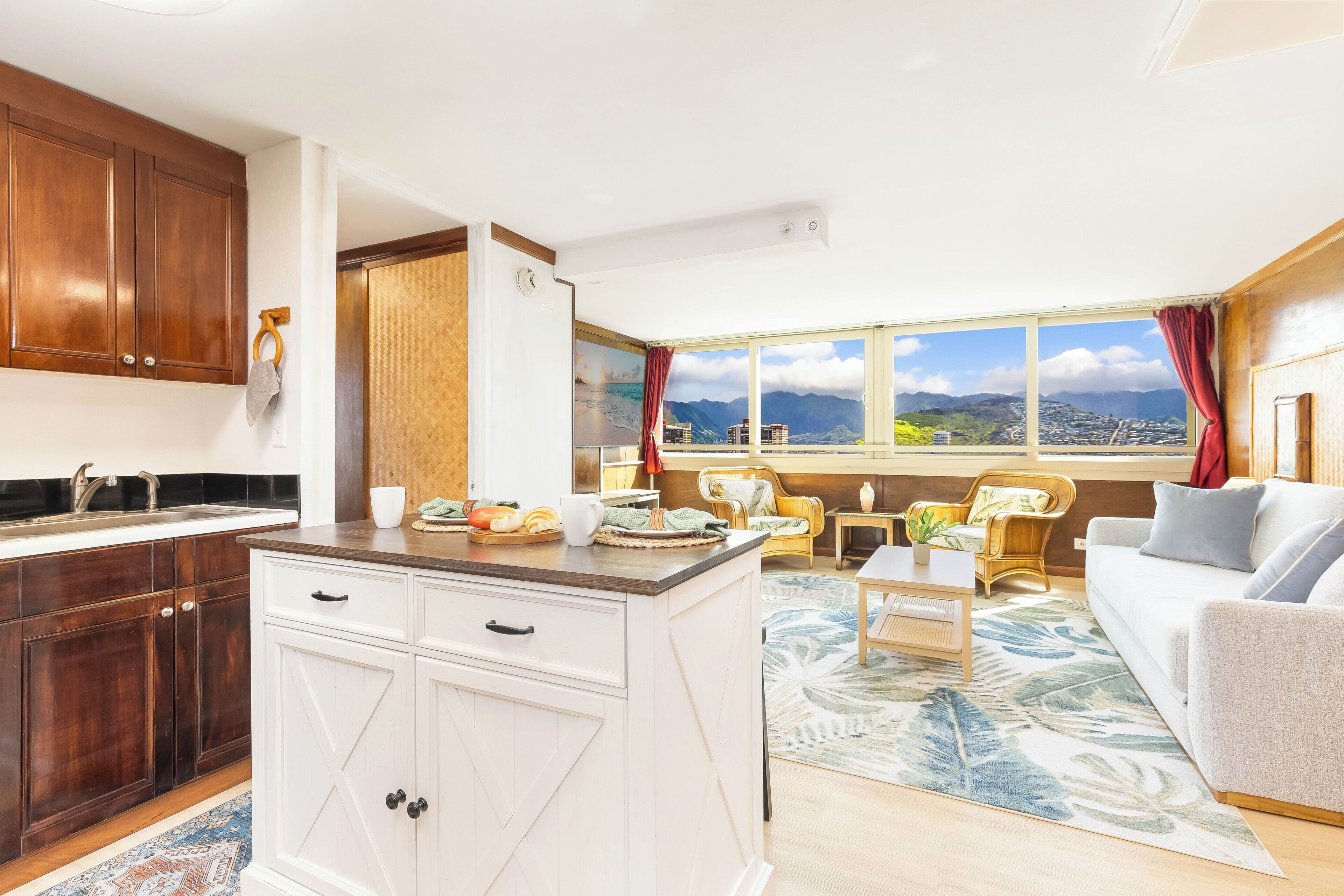 A modern kitchen with wooden cabinets, a central island, and a large window offering a view of mountains and a cityscape.