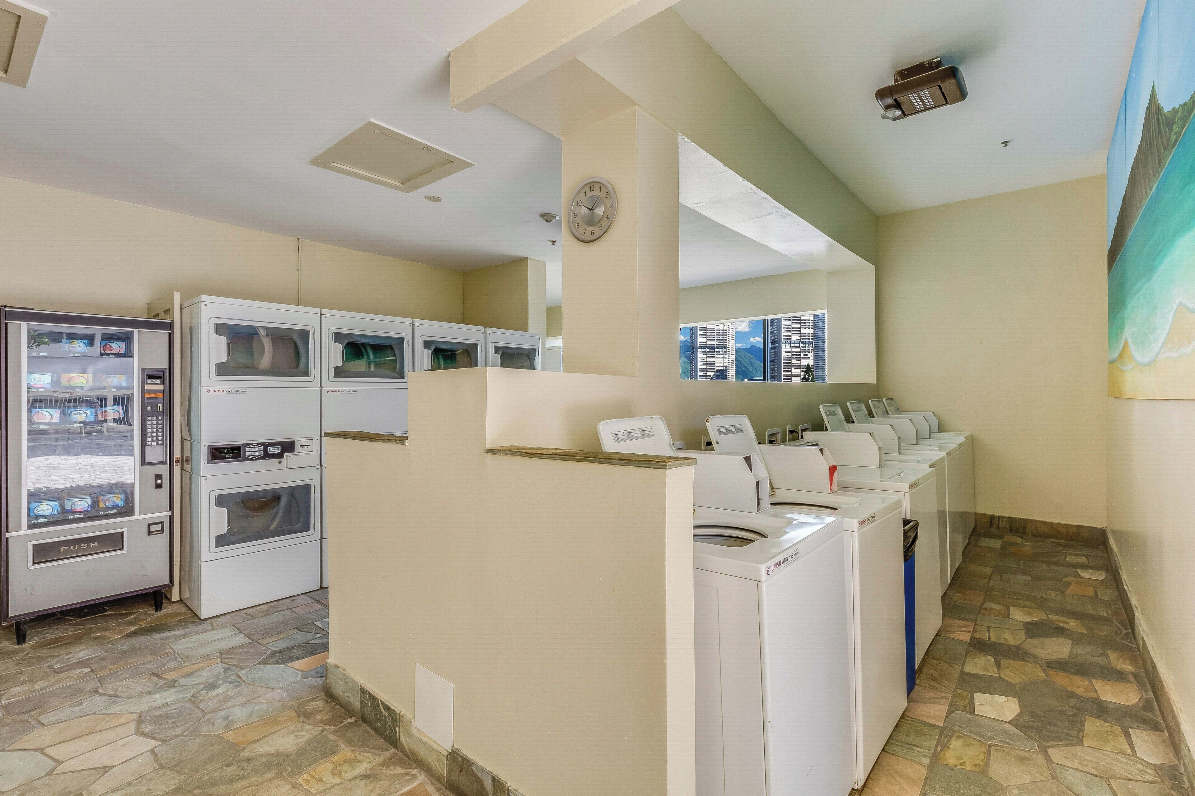 A laundry area with a vending machine, stacked dryers, and a clock on the wall.