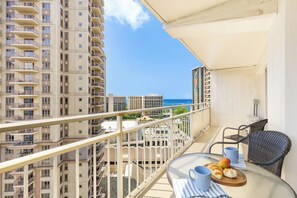 A balcony with a table, chairs, and a view of high-rise buildings and the ocean. - Ocean & City Views Family-friends Paradise Retreat at Ilikai Hotel W/kitchen (Honolulu)