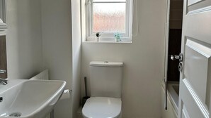 Ein kleines Badezimmer mit Toilette, Waschbecken, Fenster und Tür.