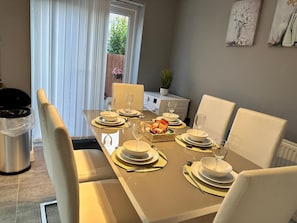 A dining area with a table set for four, including plates, glasses, and cutlery. - Modern 3-Bedroom Home in Wakefield – Sleeps 5 (Wakefield)