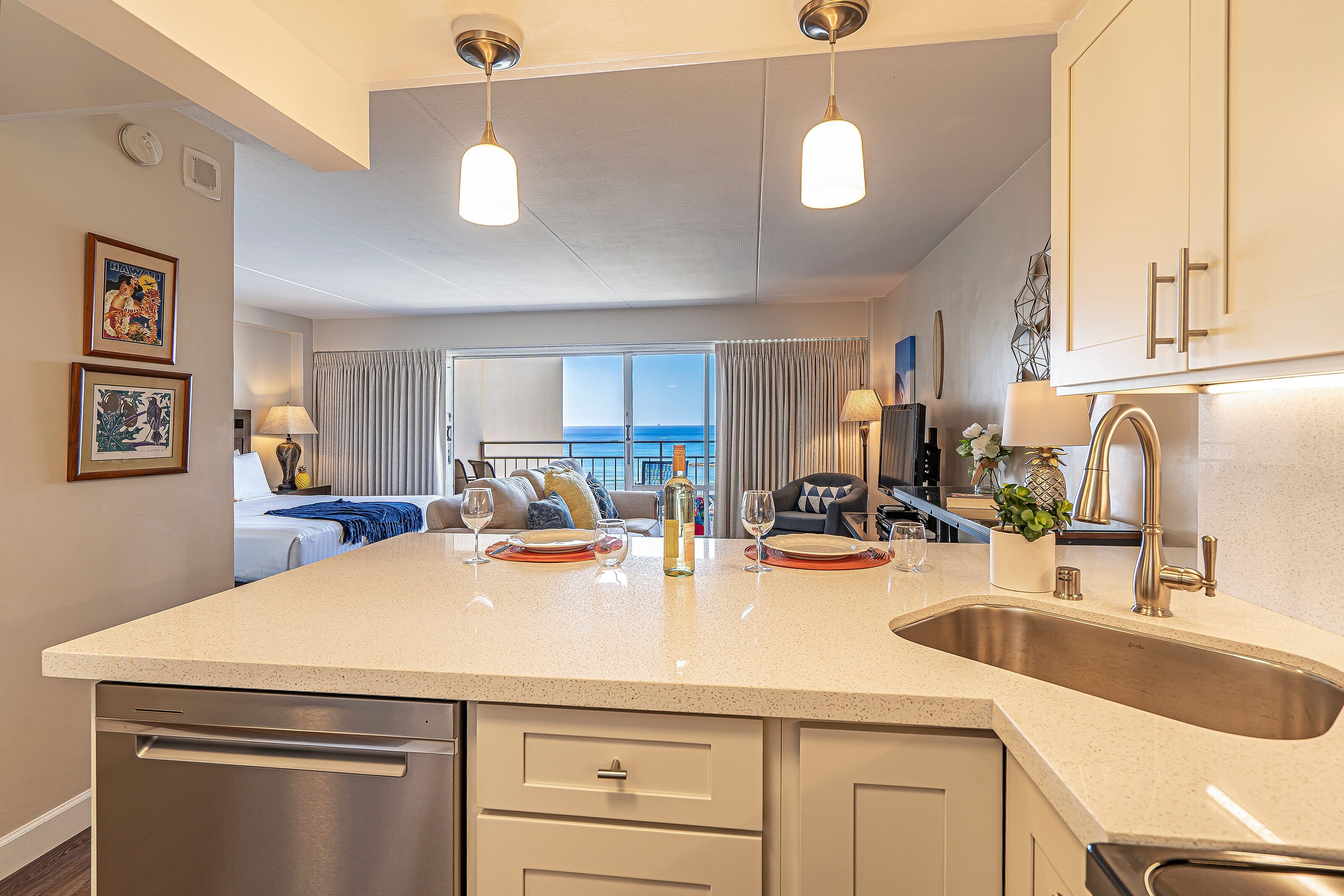 A modern kitchen with a large island, stainless steel appliances, and pendant lighting.