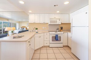 A modern kitchen with white cabinets, a microwave, stove, and a refrigerator. - City & MT Views From the Ilikai Condo by the Beach W/full Kitchen & Free Wifi (Honolulu)