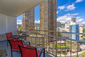 A balcony with red chairs and a table, overlooking tall buildings and a clear sky. - City & MT Views From the Ilikai Condo by the Beach W/full Kitchen & Free Wifi (Honolulu)