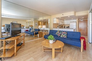 Un salon moderne avec un canapé bleu, une table basse en bois et un téléviseur posé sur un meuble en bois.