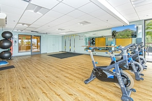 Ein Fitnessraum mit Ergometer, Spiegel und Fernsehbildschirm.