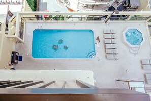Ein Dachpool mit Whirlpool, Liegestühlen und Blick auf die Stadt.