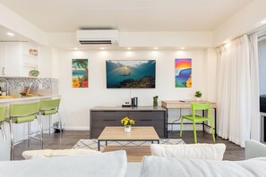 Ein modernes Wohnzimmer mit Couch, grünen Sesseln, einem Holztisch und Bildern an der Wand.