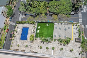 Eine Vogelperspektive zeigt ein Dach mit einem Swimmingpool, einer Grünfläche und einem Parkplatz.