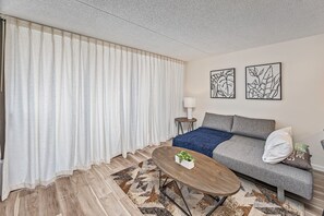 A modern living room with a sofa, a coffee table, and a lamp. - Ocean View Fully Renovated Condo at Waikiki Banyan W/amazing Amenities (Honolulu)