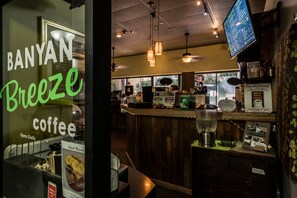 A coffee shop interior with a wooden counter, a menu board, and a coffee machine. - Ocean View Fully Renovated Condo at Waikiki Banyan W/amazing Amenities (Honolulu)