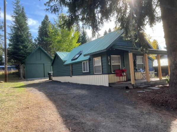A small, single-story building with a green roof and a porch area.