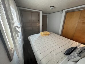 A bedroom with a bed, a wardrobe, and a window with blinds.
