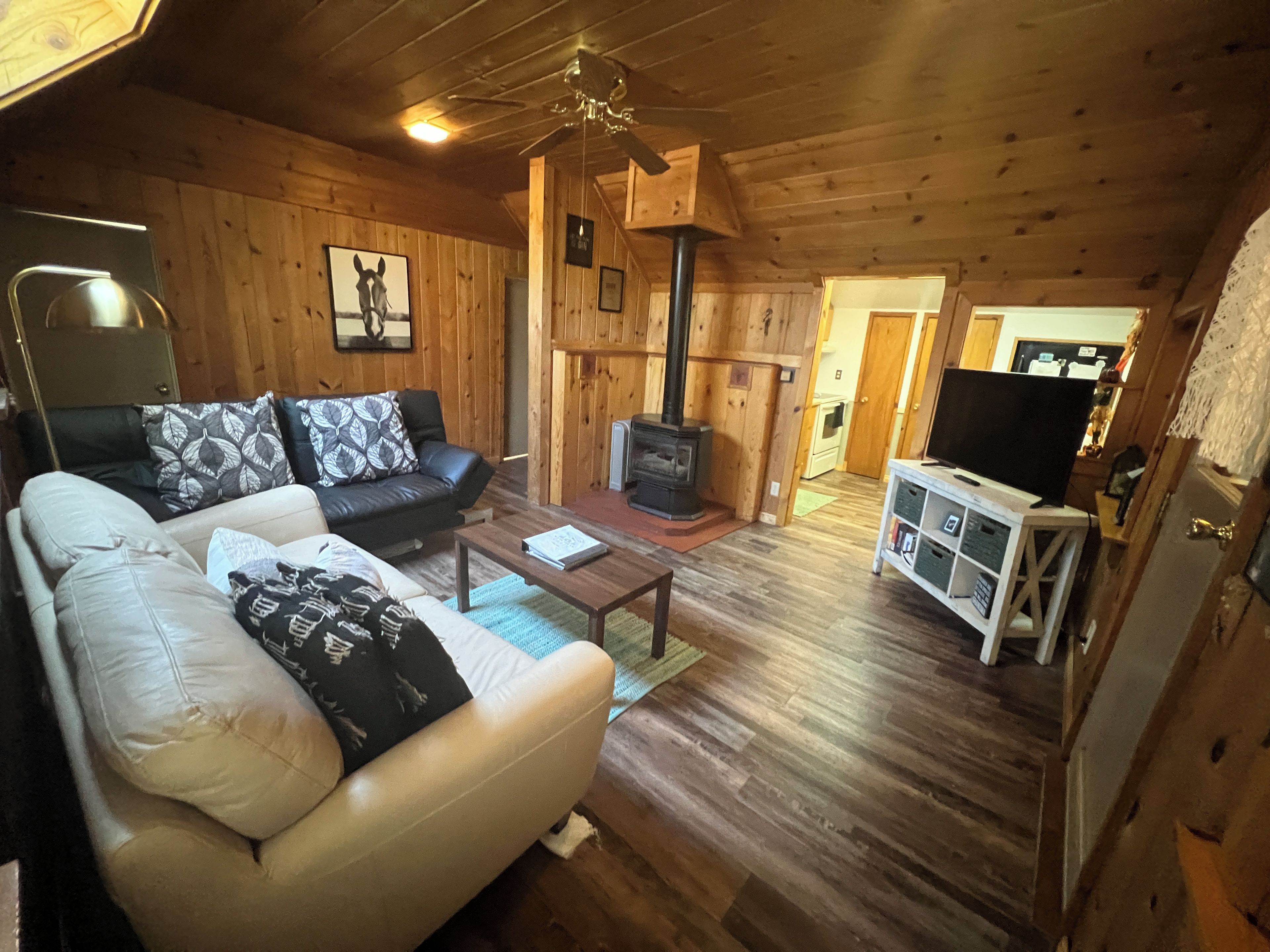 Interior acogedor de una cabaña con sofá, mesa de centro, chimenea y televisor.