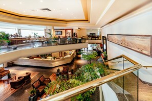 Eine mehrstöckige Hotelhalle mit einer zentralen Sitzecke, einer Bar und einer Treppe.