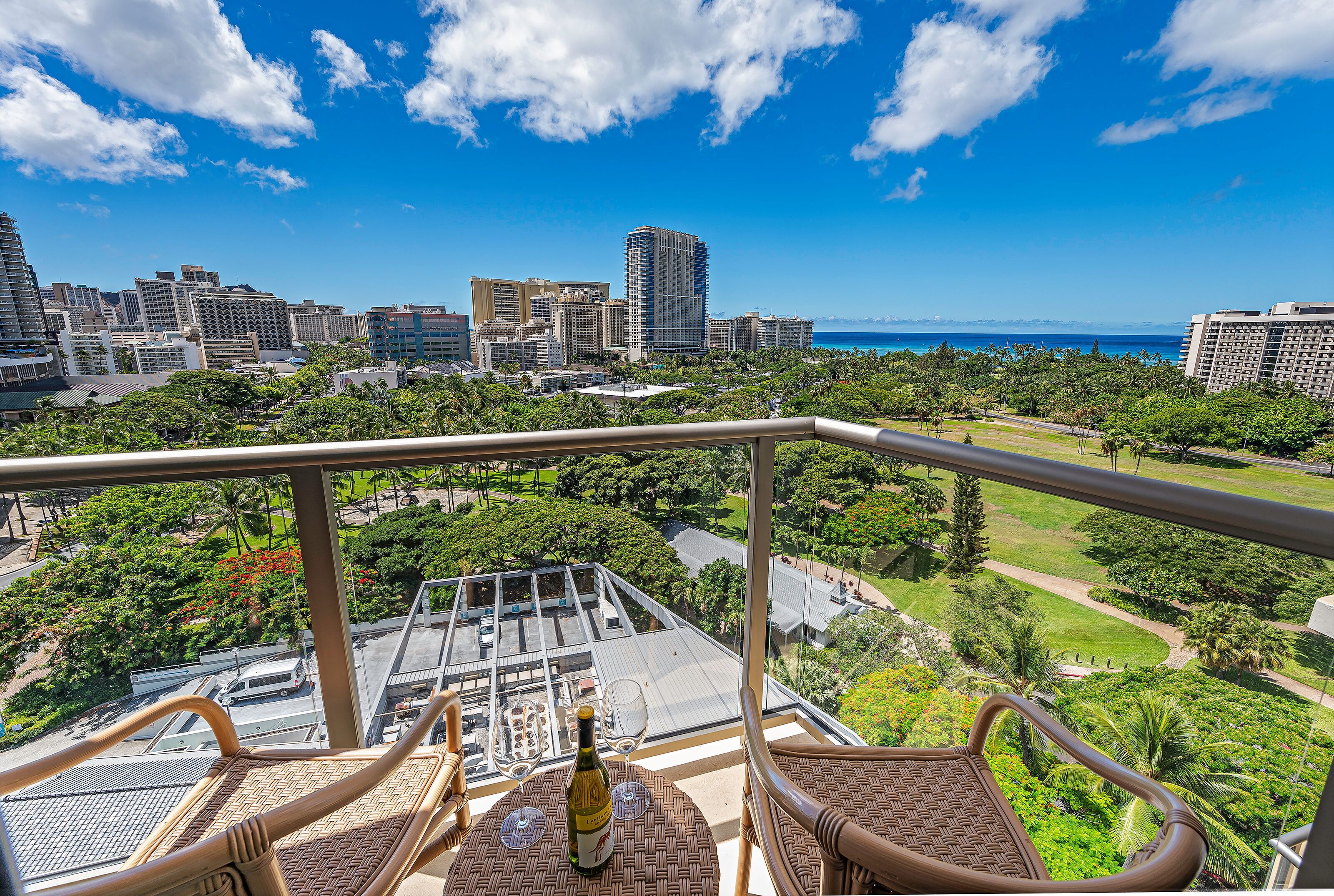 A balcony with wicker furniture, a bottle of wine, and two wine glasses.