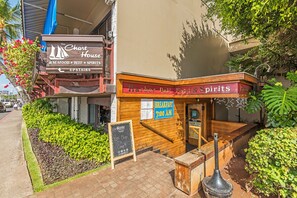 A waterfront restaurant with a sign for 'The Chart House' offering seafood, beef, and spirits, and a sign for 'Harbor Pub Food & Spirits' with a breakfast sign. - Ocean-marina Yacht Views Condo Steps to the Beach W/full Kitchen & Free Wifi (Honolulu)