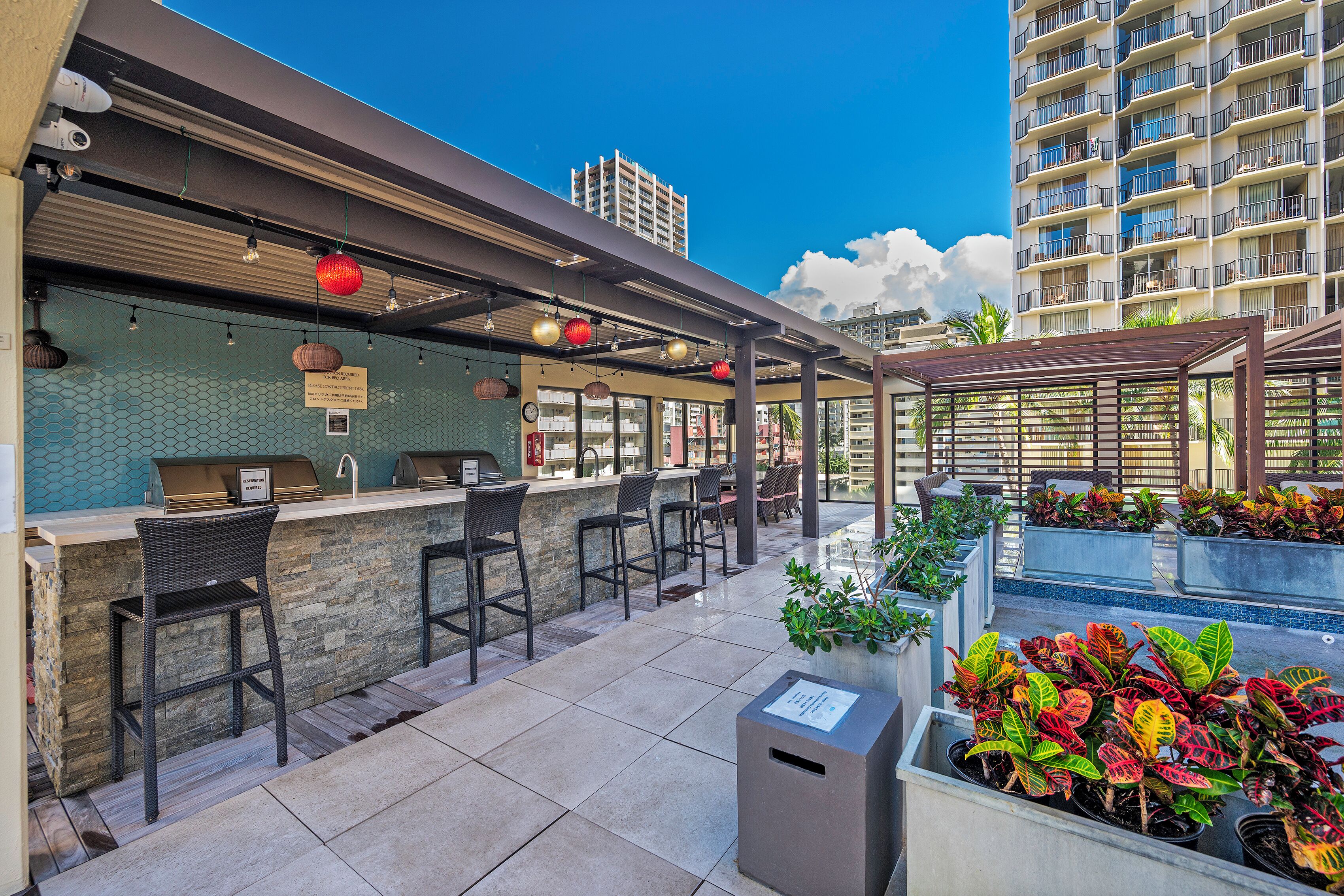 Un área de bar al aire libre con asientos, una parrilla y vistas a un edificio de gran altura.