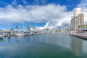 A marina with boats docked, a waterfront promenade, and modern buildings in the background. - Ocean-marina Views at Ilikai Marina W/full Kitchen Short Walk to the Beach (Honolulu)