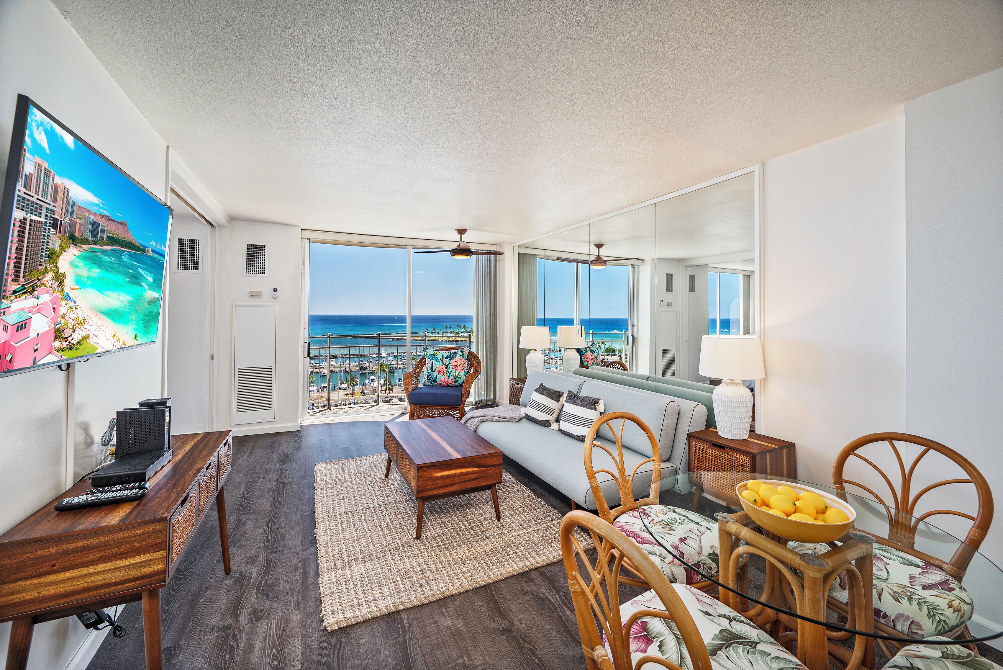 A spacious living room with a large window offering a view of the ocean, a comfortable sofa, a coffee table, and a dining area with chairs.