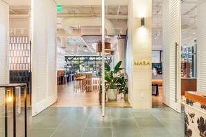 Ein modernes Interieur mit einer Rezeption, einer Sitzecke und einer großen Pflanze in einem Topf.