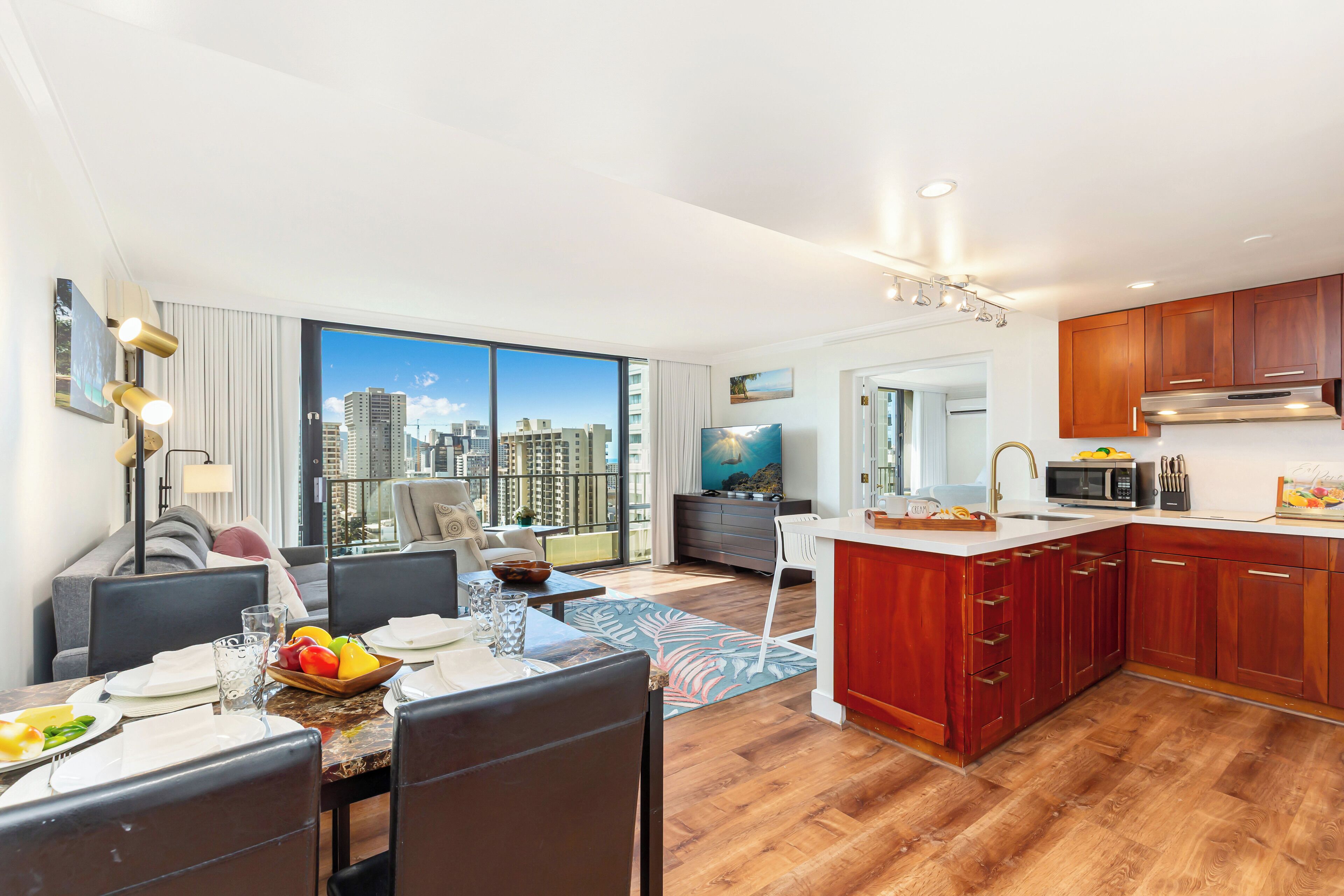 Un appartement moderne doté d’un coin repas, d’une cuisine et de grandes fenêtres offrant une vue sur la ville.