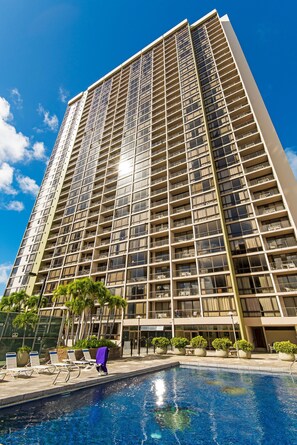 A high-rise hotel with a swimming pool and sun loungers. - Golf Course-mountain Views Condo at Waikiki Sunset Half a Block to the Beach (Honolulu)