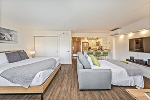 Quarto de hotel moderno com duas camas, um sofá, área de jantar e cozinha.