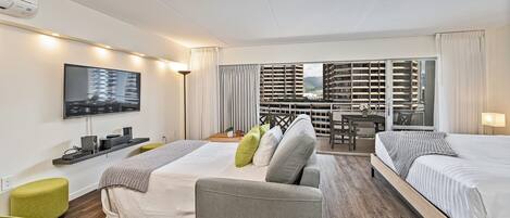 A hotel room with two beds, a sofa, a TV, and a balcony with a city view.