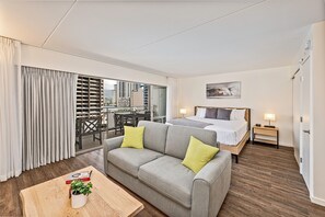 A hotel room with a bed, a sofa, a dining table, and a view of the cityscape. - Ilikai Hotel Renovated Condo Steps Away From Beach W/free Wifi & Full Kitchen (Honolulu)